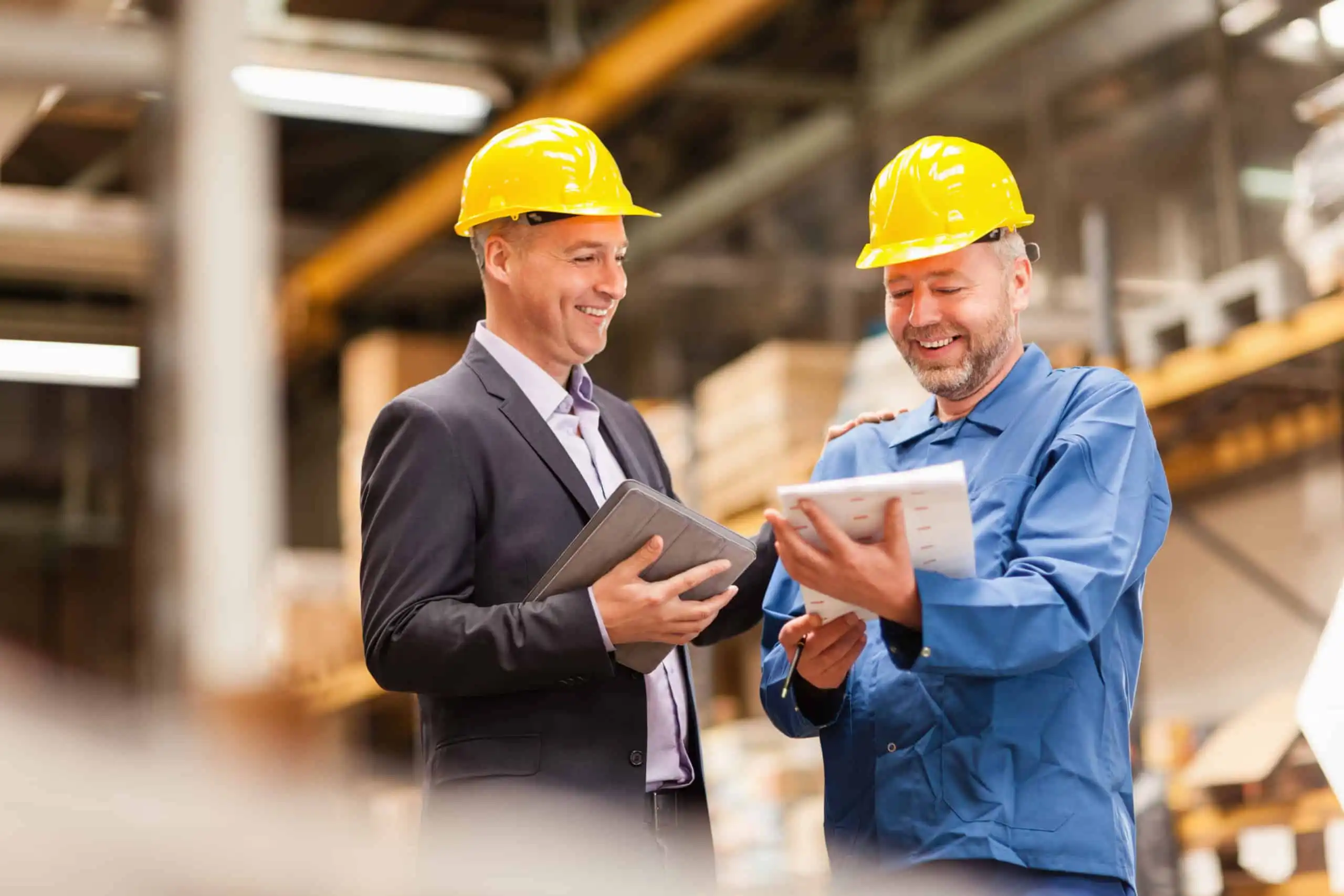 Smiling warehouse manager talking to worker.